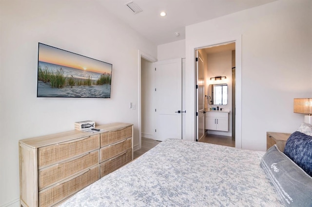 bedroom with dark wood-type flooring and connected bathroom