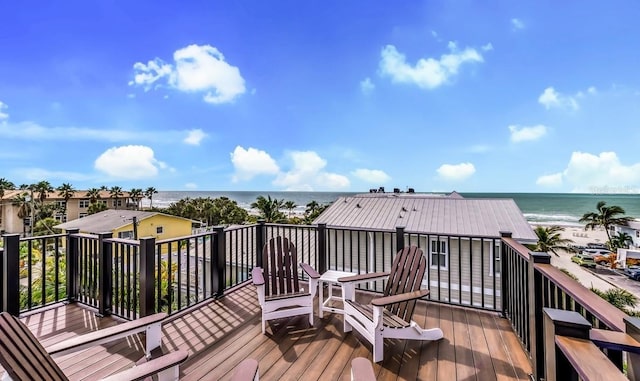 wooden deck featuring a water view and a beach view