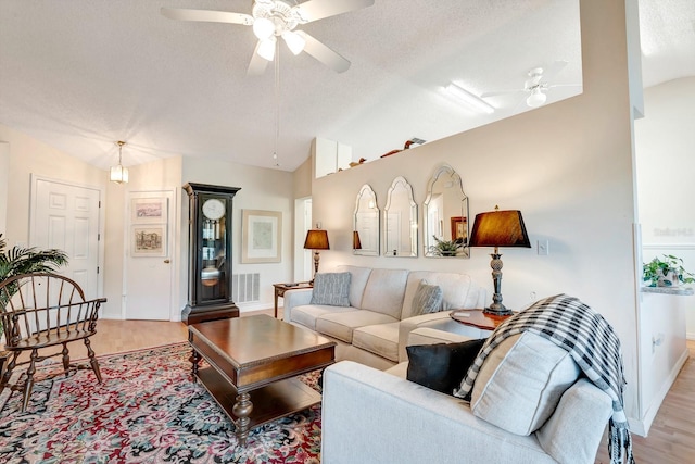 living room featuring a textured ceiling, ceiling fan, light hardwood / wood-style floors, and vaulted ceiling