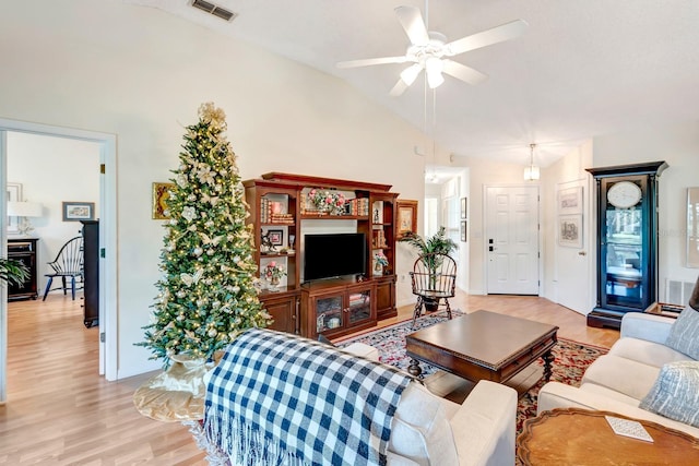 living room with ceiling fan, light hardwood / wood-style flooring, and vaulted ceiling