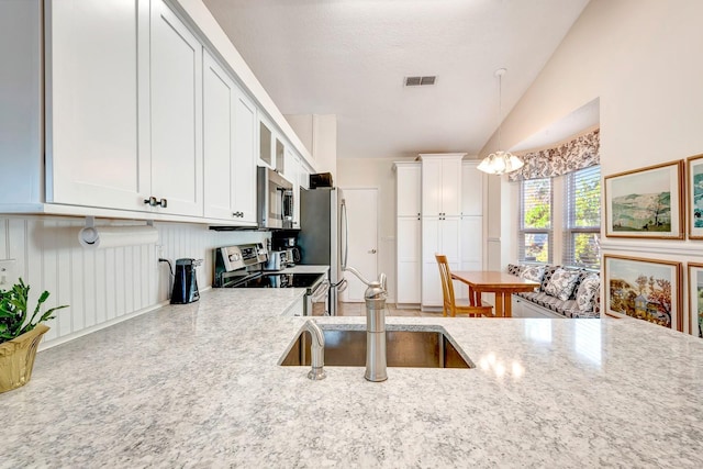 kitchen with light stone countertops, stainless steel appliances, sink, pendant lighting, and white cabinetry