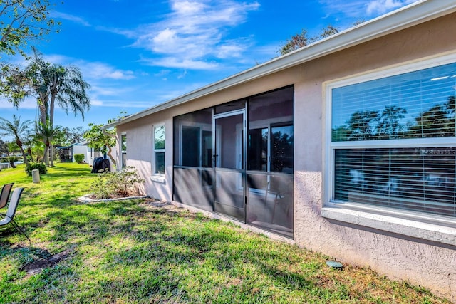 view of side of property with a yard and a sunroom