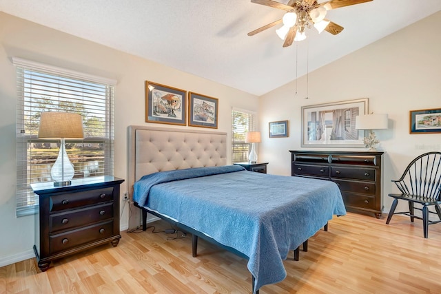 bedroom featuring multiple windows, light hardwood / wood-style floors, ceiling fan, and lofted ceiling