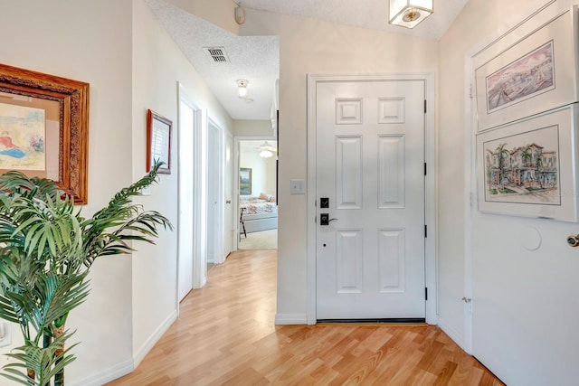 hallway featuring light hardwood / wood-style floors, lofted ceiling, and a textured ceiling