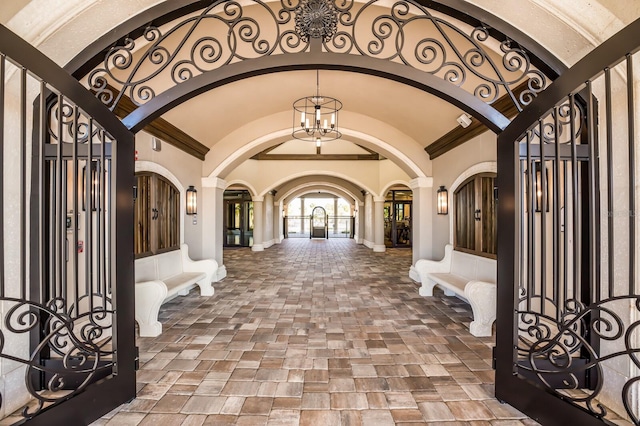 entrance foyer featuring a chandelier, vaulted ceiling, and decorative columns