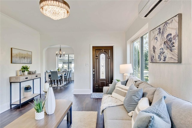 living room with a chandelier, dark hardwood / wood-style flooring, and a wall unit AC