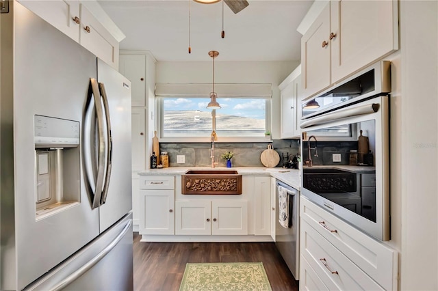 kitchen with decorative backsplash, stainless steel appliances, sink, white cabinetry, and hanging light fixtures