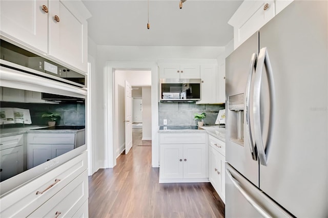 kitchen featuring appliances with stainless steel finishes, tasteful backsplash, white cabinetry, and dark wood-type flooring