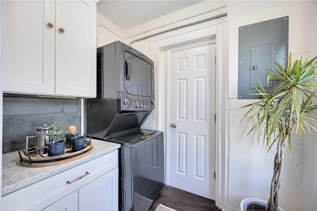 clothes washing area with electric panel and stacked washer and dryer