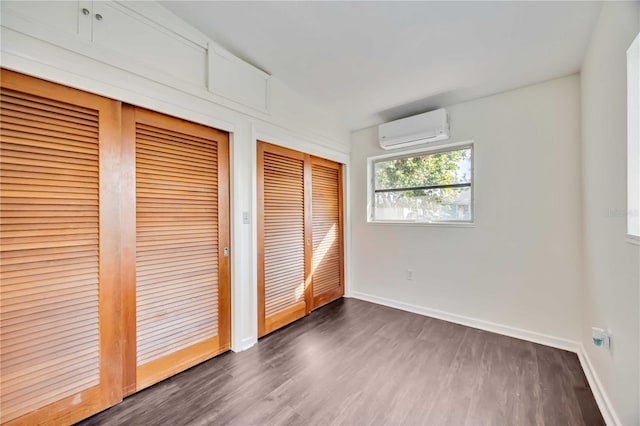 unfurnished bedroom featuring dark hardwood / wood-style floors and an AC wall unit