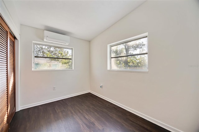 unfurnished bedroom featuring lofted ceiling, an AC wall unit, a closet, and dark wood-type flooring