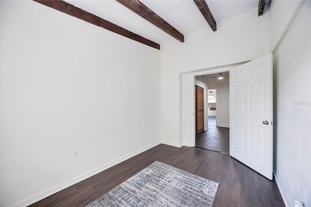 spare room featuring beamed ceiling and dark hardwood / wood-style floors