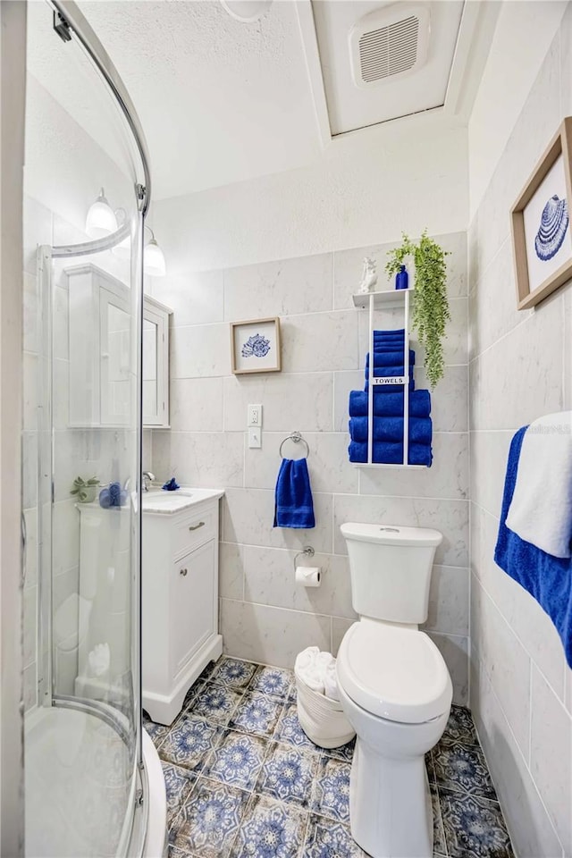 bathroom featuring vanity, tile patterned flooring, toilet, walk in shower, and a textured ceiling