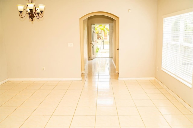 731 Cristelle Jean Dr, Ruskin, FL 33570 - empty room featuring light tile patterned floors, arched walkways, baseboards, and a chandelier