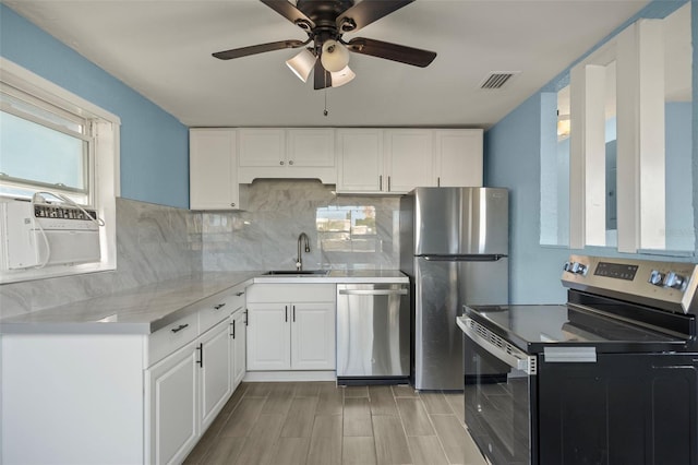 kitchen featuring white cabinets, decorative backsplash, appliances with stainless steel finishes, and sink