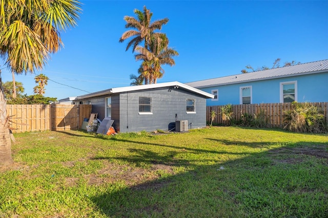 rear view of house featuring cooling unit and a yard