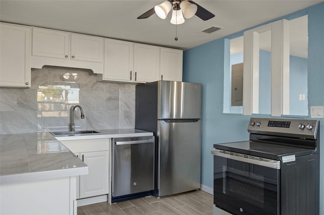 kitchen featuring decorative backsplash, appliances with stainless steel finishes, sink, and white cabinetry