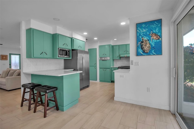 kitchen featuring a breakfast bar, a healthy amount of sunlight, kitchen peninsula, and appliances with stainless steel finishes