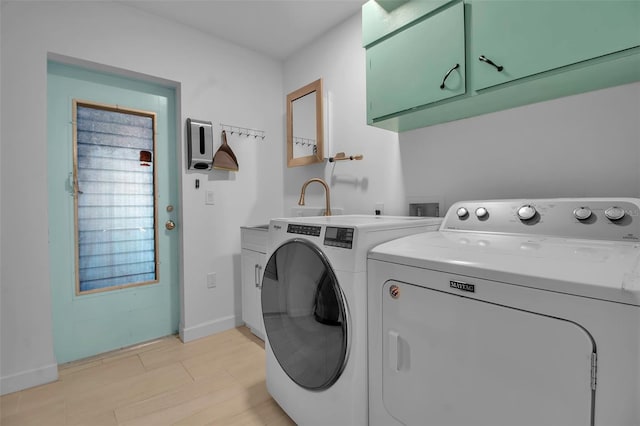 clothes washing area with washer and dryer and cabinets