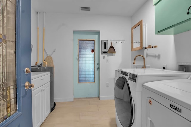 clothes washing area with washing machine and dryer and cabinets