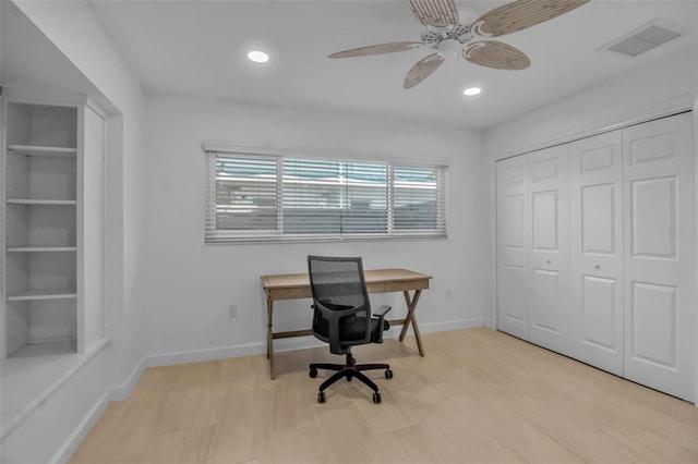 home office with ceiling fan, light wood-type flooring, and built in shelves