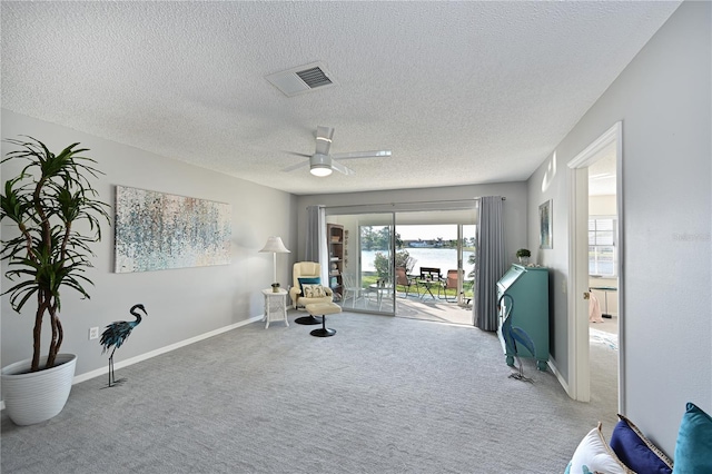 living area with baseboards, visible vents, a ceiling fan, a textured ceiling, and carpet flooring