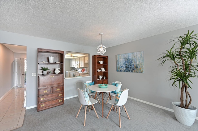 carpeted dining area featuring tile patterned flooring, a textured ceiling, and baseboards