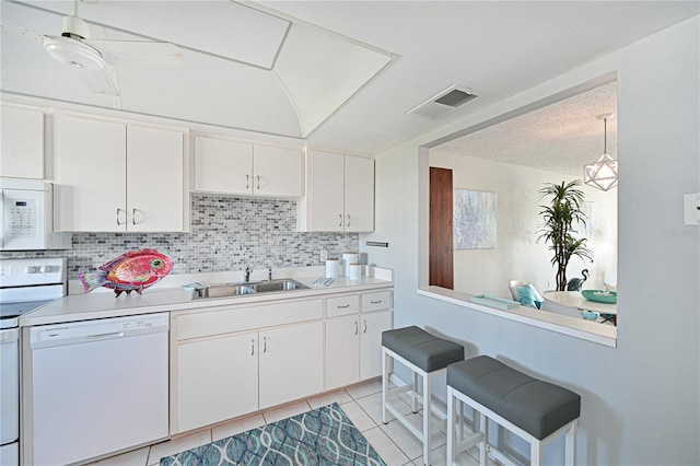 kitchen with white appliances, light countertops, a sink, and white cabinetry