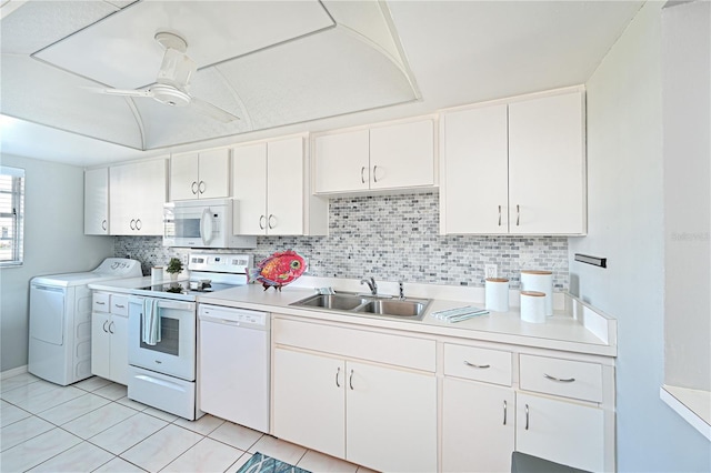 kitchen with washer / dryer, white appliances, light countertops, and white cabinets