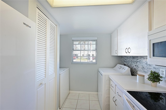 washroom featuring light tile patterned floors, cabinet space, baseboards, and separate washer and dryer