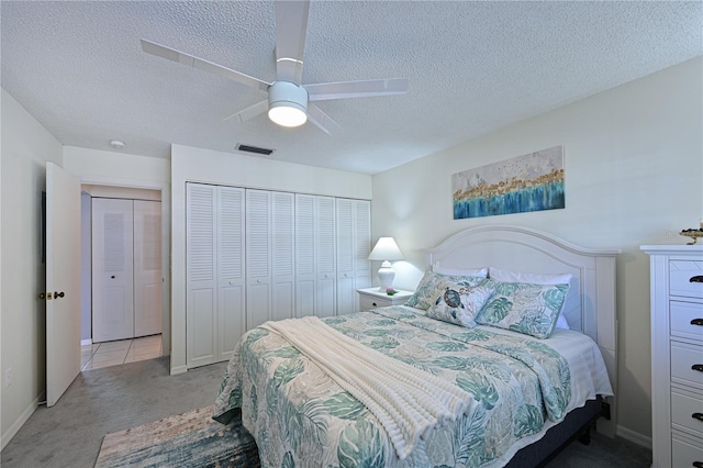 bedroom featuring a textured ceiling, light colored carpet, a ceiling fan, visible vents, and a closet