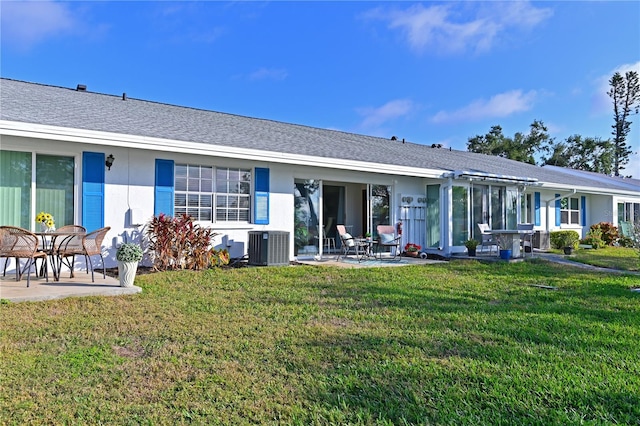 rear view of house with stucco siding, roof with shingles, a lawn, and a patio