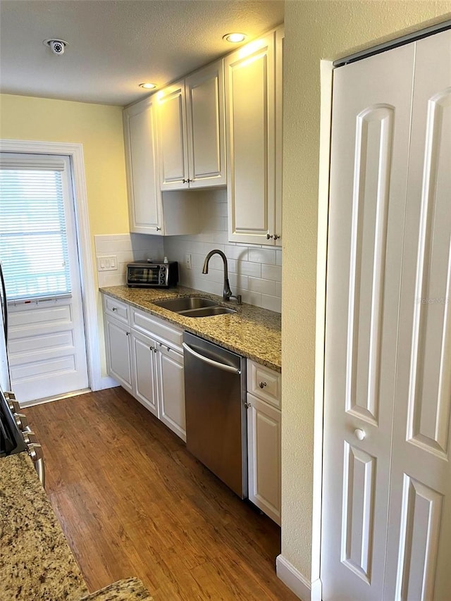 kitchen with dishwasher, backsplash, sink, hardwood / wood-style flooring, and white cabinetry