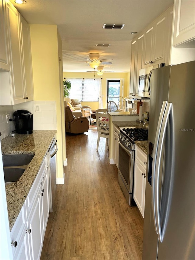 kitchen with light stone counters, light hardwood / wood-style flooring, white cabinets, and stainless steel appliances