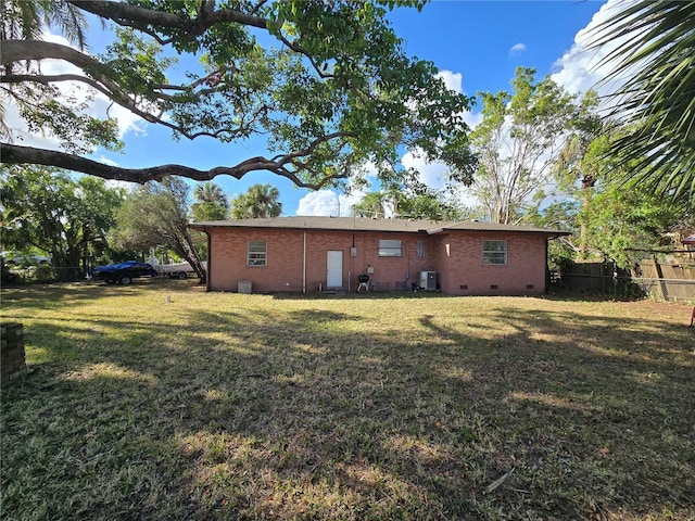 rear view of property with central AC and a yard