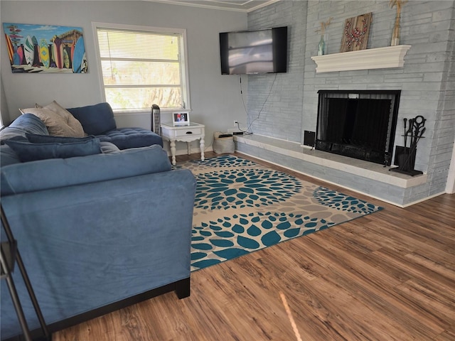 living room with hardwood / wood-style flooring, a large fireplace, and crown molding