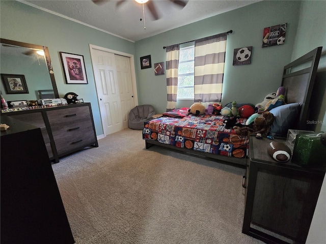 carpeted bedroom with ceiling fan, ornamental molding, and a closet