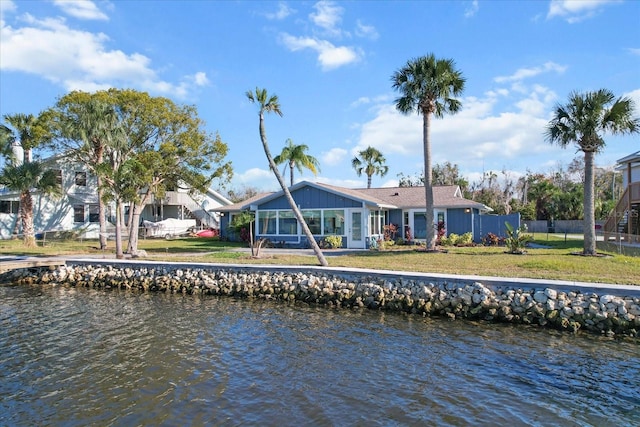 rear view of property with a lawn and a water view