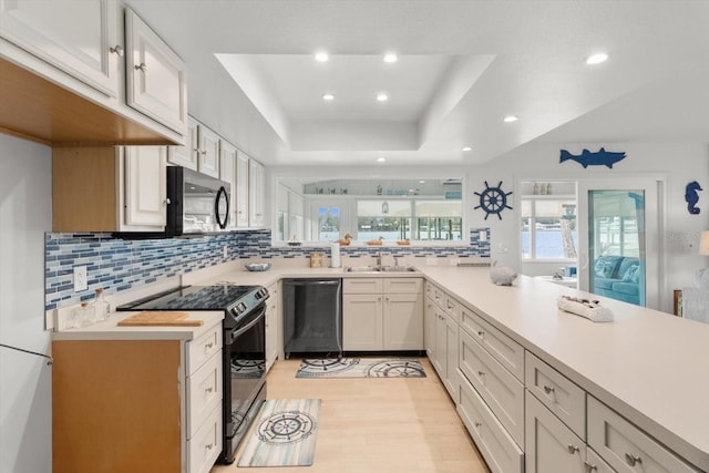 kitchen featuring tasteful backsplash, sink, appliances with stainless steel finishes, and a tray ceiling