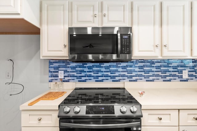 kitchen with white cabinetry, decorative backsplash, and black range