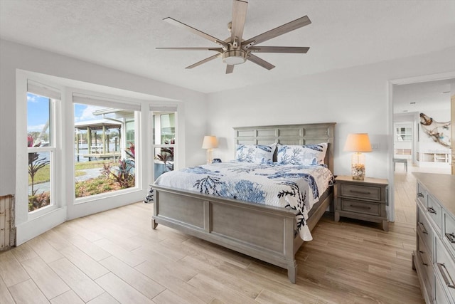 bedroom with a textured ceiling, light hardwood / wood-style floors, and ceiling fan