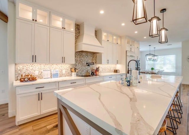 kitchen featuring white cabinetry, hanging light fixtures, a spacious island, and premium range hood