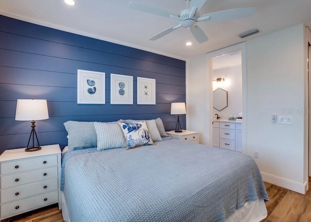 bedroom featuring ensuite bath, light hardwood / wood-style flooring, and ceiling fan