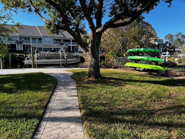 view of home's community with a dock, a yard, and a water view