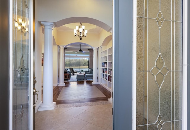 interior space featuring decorative columns, tile patterned floors, ornamental molding, built in shelves, and a chandelier