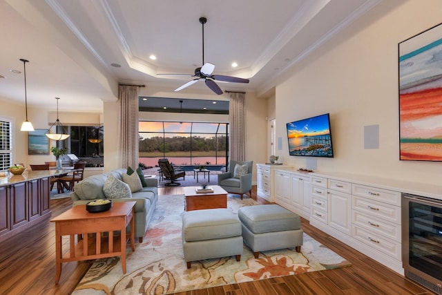 living room with a raised ceiling, ceiling fan, crown molding, hardwood / wood-style floors, and wine cooler