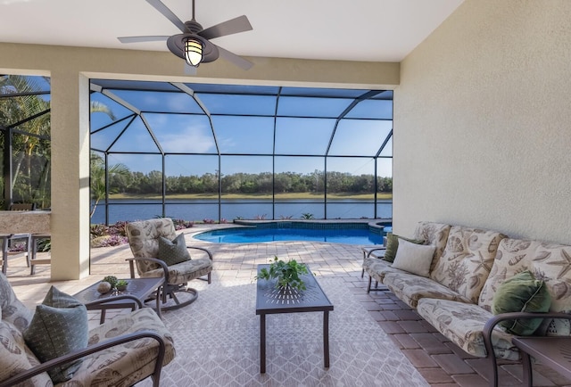 view of pool with glass enclosure, ceiling fan, a water view, and a patio