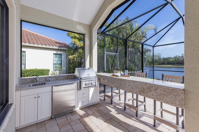 view of patio / terrace with an outdoor kitchen, area for grilling, a lanai, a wet bar, and a water view