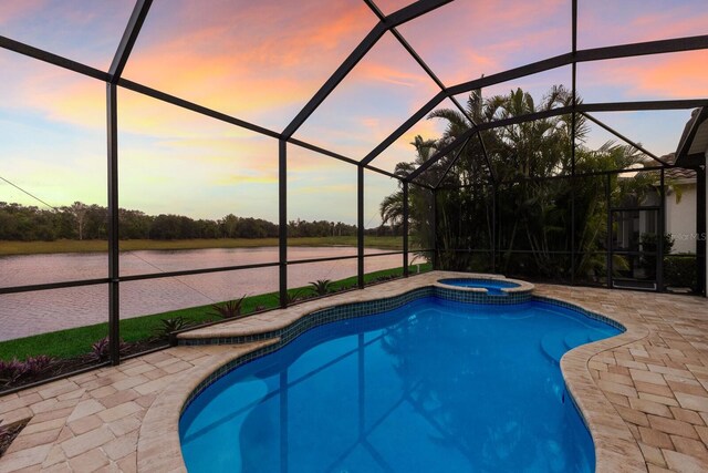 pool at dusk featuring a lanai and a patio