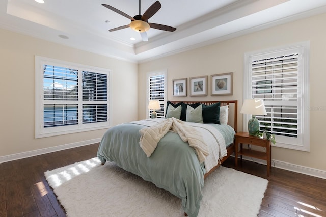 bedroom featuring dark hardwood / wood-style flooring, a tray ceiling, ceiling fan, and ornamental molding